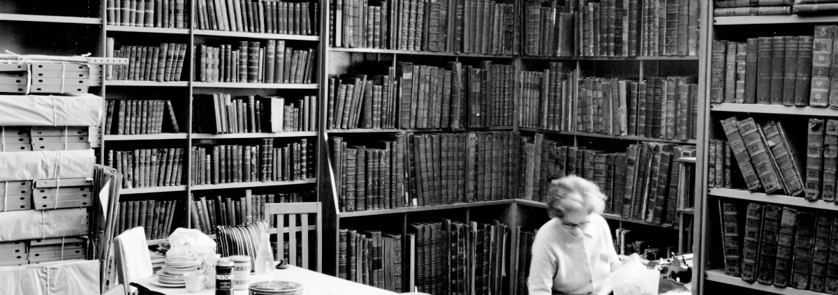 black and white image of a cosy corner of the library with books filling every shelf.