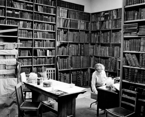 black and white image of a cosy corner of the library with books filling every shelf.