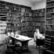 black and white image of a cosy corner of the library with books filling every shelf.