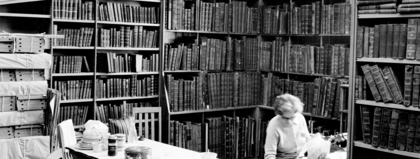 black and white image of a cosy corner of the library with books filling every shelf.