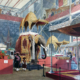 An 1851 lithograph showing the Indian display at the Crystal Palace Great Exhibition, featuring a massive taxidermy elephant under a golden canopy surrounded by Victorian visitors.