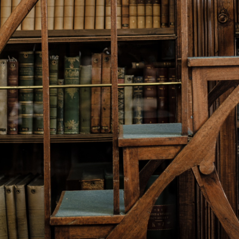image of books id a glass cabinet with wood details and wooden steps
