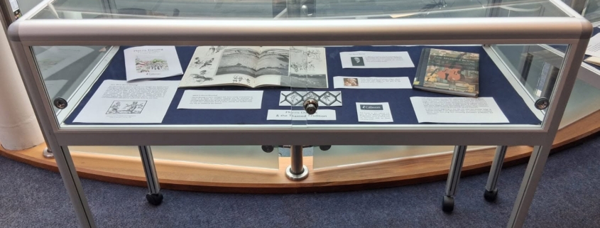 A Gibson Library exhibition display cabinet featuring various books and exhibition cards