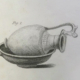 An antique engraving labeled Fig. 1 showing an ornate decorative ewer resting on its side inside a shallow, handled pan.